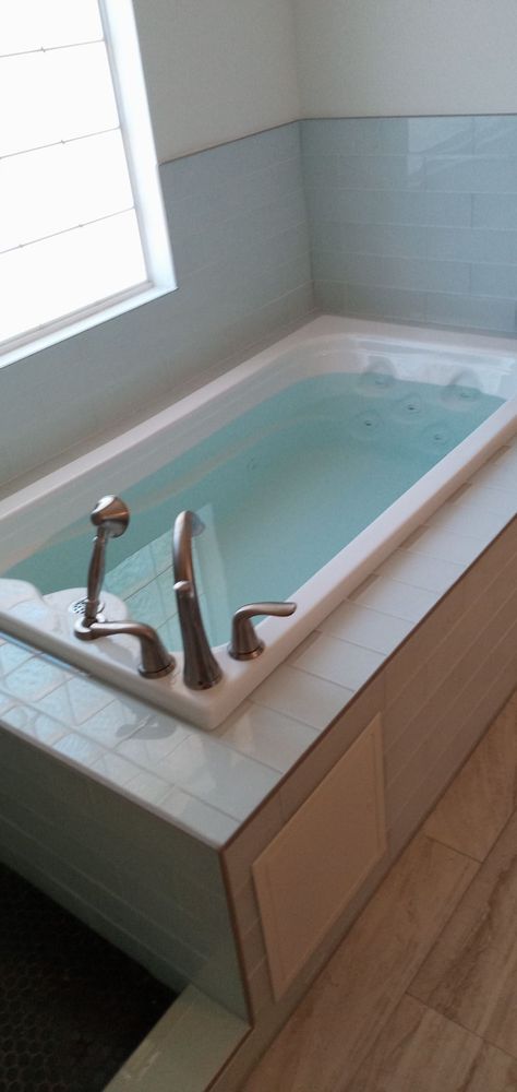 New soaking tub installed — subway tile surround, wood-look floor